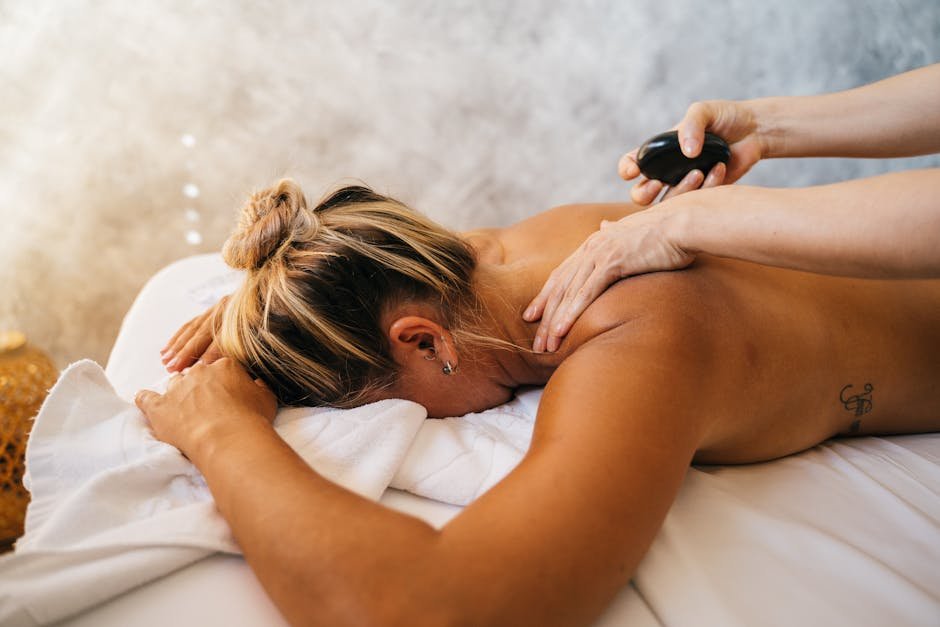 A woman enjoying a relaxing hot stone massage therapy session at a spa. Perfect for body care and relaxation.